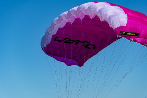 Pink and white Safire 4 canopy flying against a clear blue sky.