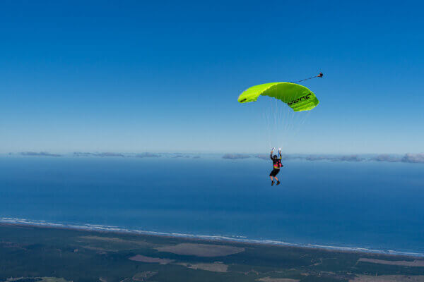 Skydiver piloting a Safire 4 canopy above Lake Taupō and the North Island landscape.