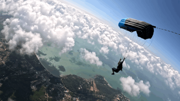 Max flying his Crossfire 3 canopy above the clouds, with the coastline visible below.