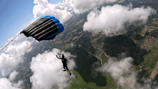 Max flying his Crossfire 3 canopy above the clouds, with the coastline visible below.