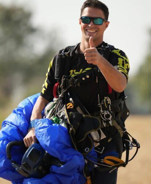 Max giving a thumbs up as he walks across the drop zone with his Petra after landing.